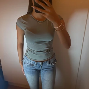 Grå tight t-shirt med kort ärm i polyamid - Grå t-shirt med tight passform och korta ärmar. T-shirten har en slät, stretchig känsla som sitter riktigt snyggt på kroppen. Storleken är S men funkar även som XS 🩶