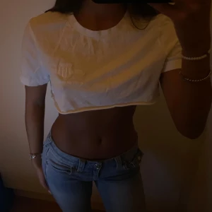 Vit croppad t-shirt från GANT - Säljer en vit croppad t-shirt från GANT med deras logga på bröstet. T-shirten är kortärmad och har en klassisk rund halsringning. Den är tillverkad i skönt material och är kort. Storleken är M och passar lösare på tjejer med XS-S 🤍