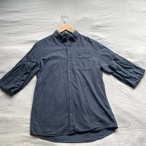 Mörkblå linne bomullsskjorta med knappar - Snygg mörkblå skjorta i bomull med klassisk krage, bröstficka och knappar hela. Perfekt för en avslappnad men stilren look.