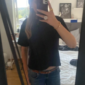 Svart stickad T-shirt från Gina  - Enkel svart t-shirt med loose passform och korta ärmar. Modellen är rak och något boxig, perfekt till jeans eller shorts. T-shirten är i mjukt material och har en klassisk rund halsringning. Från Gina tricot 