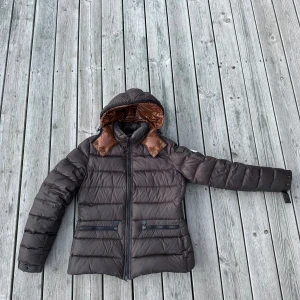 Moncler vinterjacka dam - Äldre modell av Moncler vinterjacka i brun färg. Väldigt bra skick 8/10, ända som drar ner skicket från 10 är att det saknas två knappar i nacken (bild 5) och bältet vid midjan saknas, men det påverkar ej funktionen. Säljer åt min tjej som inte längre använder jackan. Storleken är 3 och motsvarar S. Skriv gärna vid frågor eller funderingar!