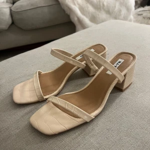Klackar  NA-KD - Stilrena beige sandaler från NA-KD med fyrkantig tå och blockklack. Skorna har krokopräglat mönster och tunna remmar över foten och runt vristen. Använda vid ett tillfälle🌸