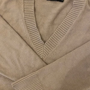 Beige stickad v-ringad tröja BIK BOK - Beige stickad tröja från BIK BOK i storlek S. Tröjan har v-ringning, ribbade muddar och nederkant samt långa ärmar. Perfekt för lager-på-lager och chill vibes.