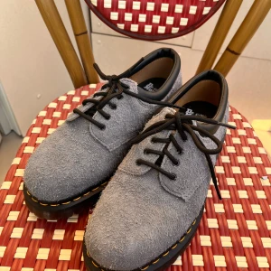 Grå-blå Dr. Martens 8053 i mocka - Grå-blå dr.martens i mocka. Aldrig använda men ingen kartong! Strl 42. Denna modell har lite skönare  och mjukare häl som inte gräver lika mycket mot hälen. 