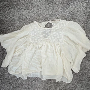 Vit blommig blus från Zara  - Säljer en luftig vit blus från Zara Trafaluc i storlek M. Blusen har broderade blommor på bröstet, vida ärmar och en söt öppning i nacken. Materialet är mjukt och lätt, perfekt för varma dagar. Den sitter som en xs 