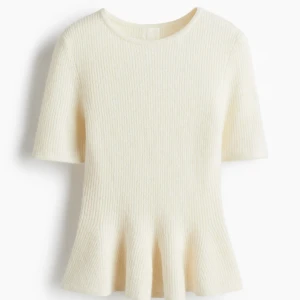 Krämvit stickad topp med kort ärm - Superfin krämvit stickad topp med korta ärmar och rund hals. Toppen har en lätt utsvängd nederkant som ger en snygg siluett. Perfekt att styla med jeans eller kjol för en clean look. Ny med prislapp💕