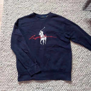 Mörkblå sweatshirt från Polo Ralph Lauren🙌🤩 - Säljer en unik mörkblå sweatshirt från Polo Ralph Lauren med klassiskt polospelartryck i vitt och rött framtill. Tröjan är i storlek S och väldigt sällsynt 🙌🤩