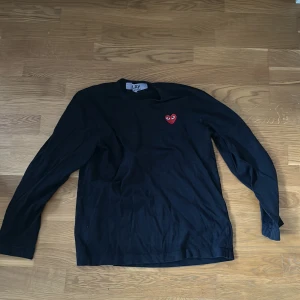 Comme des Garçons longsleeve - Svart långärmad tröja från Comme des Garçons PLAY med det ikoniska röda hjärtat broderat på bröstet. Strl L men passar S/M