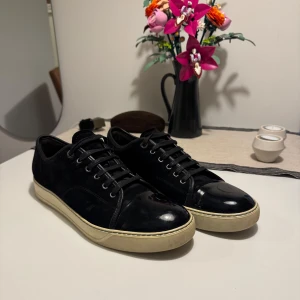 Lanvin sneakers, DBB1 Patent Toe Cap - ! OBS ! Har tyvärr inte skolådan kvar, den slängdes av misstag. - Lanvin sneakers som används för lite och ska därför säljas. Fick dessa som födelsedagspresent förra sommaren och de har använts ca 5 gånger. 9/10 i skick enligt mig, det enda som märks är använt är sulan.