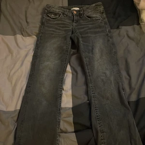 Svarta jeansbyxor från Gina Tricot 152 - Svarta jeansbyxor från Gina Tricot i storlek 152. Byxorna har raka ben, klassisk femficksdesign och snygga detaljer på bakfickorna med knappar. Materialet är jeans och färgen har en lätt tvättad look för en cool vibe.