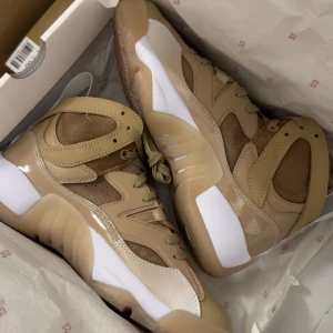 Beige och vita sneakers i box - Säljer ett par riktigt snygga sneakers i beige och vitt med coola paneler och detaljer. Skorna har snörning, rund tå och en chunky sula. Materialmix av syntet och textil ger en modern vibe. Perfekta för dig som vill sticka ut med stilrena färger.