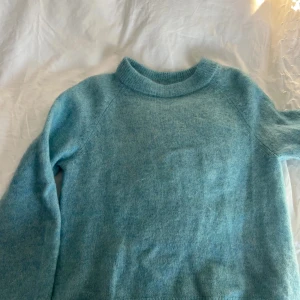 Ljusblå stickad tröja från H&M - Väldigt fin ljusblå stickad tröja från H&M. Perfekt för kyliga dagar med sin mjuka och bekväma passform. Tröjan har långa ärmar och en rund halsringning. Använd ungefär tre gånger💗