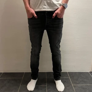 Svarta slim jeans Jack & Jones - Svarta slim fit jeans från Jack & Jones, modell Glenn (W28 L30). Jeansen har klassisk femficksdesign, snygg tvättad finish och smal passform. Tillverkade i stretchig denim för extra komfort. Perfekta för dig som gillar en stilren och modern look.