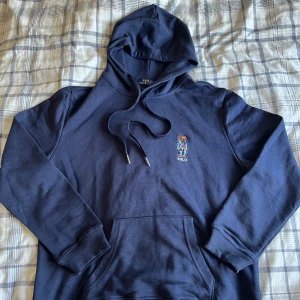 Mörkblå hoodie Polo Ralph Lauren - Mörkblå hoodie från Polo Ralph Lauren med broderad nalle på bröstet.  Ovanlig och sjukt snygg hoddie i storlek XS. Vid snabb affär kan gå ner i pris! 