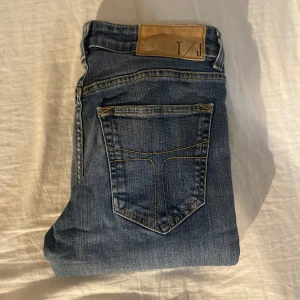 Blåa tiger of sweden jeans - Snygga blå jeans från tiger of sweden med klassisk femficksdesign och gul kontrastsöm. Jeansen har normal midja och är tillverkade i stretchig bomullsdenim för en bekväm passform. Perfekta till sneakers eller boots.