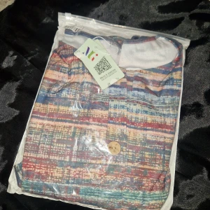 Färgglad blus med mönster - Säljer en lös och bekväm blus från Maria & Gabrielle i storlek 3XL. Blusen har ett färgstarkt, abstrakt mönster i blått, rött, beige och rosa toner. Den har rund halsringning, trekvartsärmar och en dekorativ knapp framtill. Perfekt för dig som gillar unika plagg!