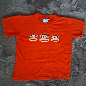 Röd Paul Frank t-shirt med aptryck - Cool röd t-shirt från Paul Frank med tre klassiska Julius-apans ansikten tryckta på bröstet. T-shirten har rund hals och korta ärmar, perfekt för en avslappnad och lekfull stil. Tillverkad i mjuk bomull för skön känsla hela dagen. Sitter mer som XXS även fast det står M 
