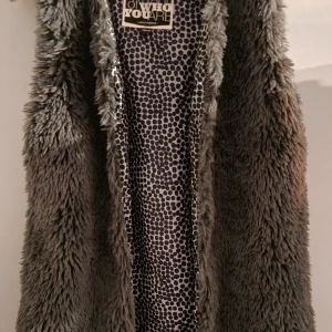 Grå pälsväst från Emoi Refined 158/164 - Säljer en fluffig grå pälsväst från Emoi Refined med coolt prickigt foder i svart och vitt. Västen har en rak passform och är perfekt för att ge din outfit extra edge. Fodret har ett mönster som sticker ut och gör västen unik.