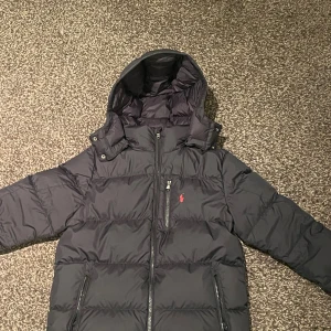 Svart pufferjacka Polo Ralph Lauren - Det är en svart pufferjacka från Polo Ralph Lauren med huva 👌🏼. Det är en perfekt jacka nu till vintern som passar till alla tillfällen ❄️. Den är väldigt varm och skön. Jag är 170cm lång. Jackan är i nyskick och det är inget negativt med den. 