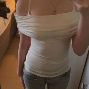 Vit offshoulder topp med drapering - Säljer en vit offshoulder topp. Toppen är figurnära och har en stilren. Materialet känns mjukt. Säljer för jag köpte en för liten storlek Fråga om du undrar ❤️