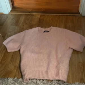 Ljusrosa stickad T-shirt - Supermysig ljusrosa stickad tshirt ifrån GinaTricot med korta ärmar och rund hals. Storlek M men passar mig som vanligtvis har xs/s. Använt en gång.