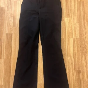 Svarta bootcut byxor från BikBok - Svarta byxor från BikBok i storlek 34 med bootcut-silhuett. Snyggt klassisk modell med hög midja och raka ben som får en lätt utsvängd form nertill. Perfekta till sneakers eller boots. Materialet känns mjukt och följsamt.