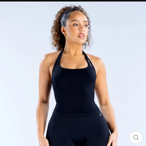 Svart halterneck linnetopp från Dfyne - Säljer en svart halterneck linnetopp från Dfyne med stilren design och diskret logga på axelbandet. Toppen är tight och passar perfekt till träning eller gym. Materialet är stretchigt och följsamt för maximal rörelsefrihet.