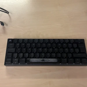 Corsair K65 RGB MINI 60% Mechanical Gaming Keyboard - Kompakt mekaniskt tangentbord med RGB-belysning, perfekt för gaming och skrivbord med begränsat utrymme. Modell: K65 RGB MINI, 60% layout. Tangenter och chassi i gott skick, inga synliga defekter. Levereras med USB-C kabel.