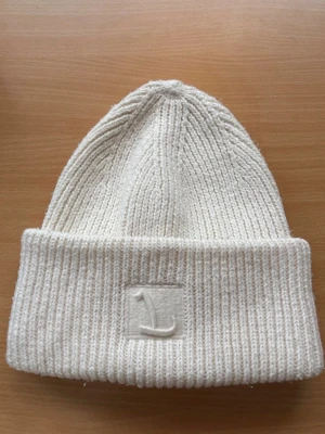 Vit ribbstickad mössa från Lindex - Jättefin mössa från Lindex. Använd en del men är ändå i fint skick och har inga synliga fläckar. 