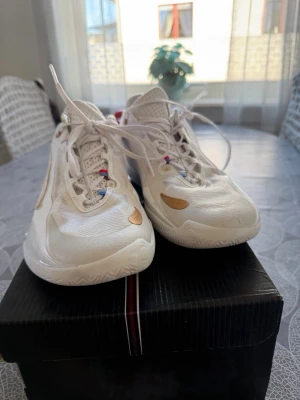 Vita basketdojor från Li-Ning Way of Wade - Säljer ett par fräscha vita Li-Ning Way of Wade basketdojor med guldiga detaljer och cool design. Skorna har mesh-ovandel för bra andningsförmåga och slitstark sula. Perfekta för dig som vill sticka ut på basketplanen! Har haft på mig de max 5 gånger 