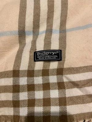 Klassisk Burberry Halsduk - Burberry halsduk 🩷  Klassisk Burberry-halsduk i det välkända rutmönstret. En tidlös favorit som aldrig går ur stil.  ✨ Detaljer: – Material: Lammull – Färg: Rosa/Vit/Ljusblå/Svag brun – Mått: ~165 cm x 33 cm – Skick: Mycketbra – Original: ja  Perfekt till höst & vinter och funkar både casual och uppklätt. Skickas snabbt 📦 Pris kan diskuteras.