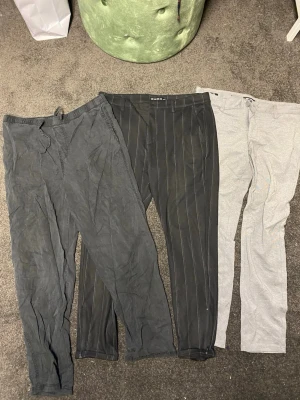 3-pack kostymbyxor herr W33 L32 - Säljer tre par kostymbyxor i olika stilar: ett par svarta med kritstrecksrand, ett par mörkgrå och ett par ljusgrå. Perfekta för dig som vill ha klassiska och stilrena byxor till garderoben. Alla byxorna har normal passform och är i mjukt tyg.