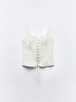 Vit randig korsettopp med snörning - Trendig vit korsettopp med tunna vertikala ränder och snörning framtill. Toppen har breda axelband och croppad passform, perfekt till jeans eller kjol. Snygg och stilren design som lyfter vilken outfit som helst.