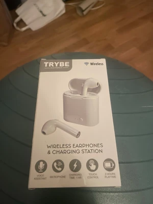Vita trådlösa hörlurar Trybe - Säljer ett par vita trådlösa hörlurar från Trybe med laddningsetui. Hörlurarna har touchkontroll, mikrofon och stöd för röstassistent. Upp till 2 timmars speltid och laddas enkelt i det medföljande etuiet. Perfekta för musik, samtal och träning.