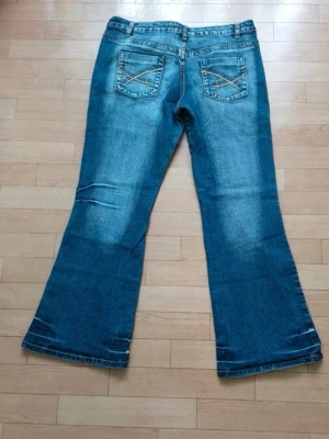 Blå bootcut jeans med slitningar - Säljer ett par lågmidjade bootcut jeans! Mått: Längd: 94 cm, Innersöm: 72 cm, Midja: 46 cm, Innersöm: 26.