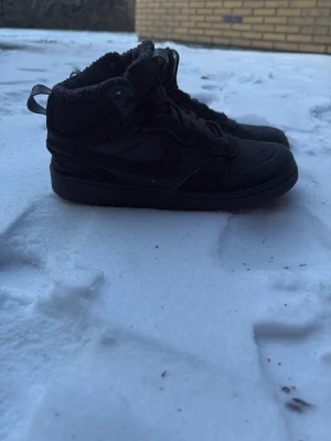 Svarta Nike kängor med foder - Snygga svarta kängor från Nike med högt skaft och mjukt foder på insidan. Skorna har klassisk Nike-logga på sidan, snörning och robust sula. Perfekta för kalla dagar när du vill ha både stil och komfort. Storlek 40 perfekt när det är kallt. Pris kan diskuteras 