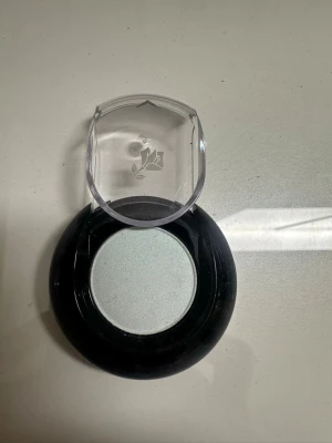 Ljusblå ögonskugga från Lancôme - Snygg ljusblå ögonskugga från Lancôme i rund dosa med svart botten och genomskinligt lock med rosdetalj. Perfekt för att skapa en fräsch och cool look. Pudrig formula som är lätt att applicera och blenda.