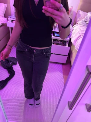 Svarta raka jeans med låg midja - Säljer ett par svarta jeans med låg midja och raka ben. Jeansen har klassisk femficksdesign och knappgylf. Passar perfekt till en avslappnad och trendig stil. Materialet är denim och färgen är djupsvart.