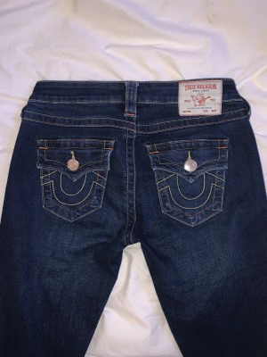 True Religion Joey Low Rise Flare Jeans - Säljer mina True Religion jeans i modellen Joey low rise flare! Nyköpta på Pondus för cirka ett år sedan så i väldigt bra skick men byxorna har lite slitningar längst ner (visas i tredje bilden) men det är inget man tänker på💗 skriv vid frågor!
