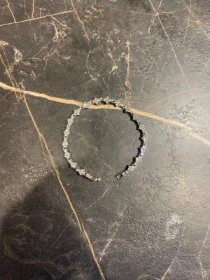 Glittrigt strassarmband i silver - Snyggt armband med glittrande strasstenar i silverfärg, designat i en rad med blommönster. Låset är metallfärgat och armbandet kommer i en holografisk förpackning från Crystal. Perfekt för att ge din outfit extra bling.