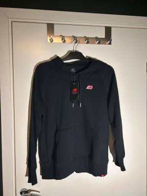 Svart hoodie från New Balance - Hoodie från New balance, helt ny tags finns kvar, aldrig använt, perfekt som en vanlig hoodie eller träningströja! Pris ej hugget i sten , ställ gärna frågor!