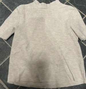 Beige ribbad polotopp från Zara - Säljer en beige ribbad polotopp från Zara Trafaluc. Toppen har korta ärmar och en högre krage med lätt vågig kant. Perfekt för dig som gillar en enkel men stilren stil.💕💕