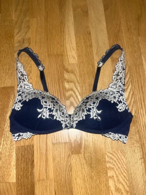 Intimissimi bh mörkblå - Säljer en mörkblå linnetopp med vacker ljus spets och broderade detaljer. Toppen har tunna axelband och en feminin form med blommigt mönster i spetsen. Perfekt för dig som gillar romantisk och elegant stil.