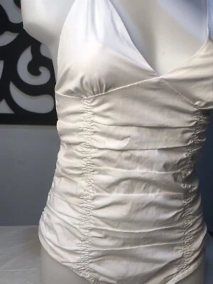 Vit omlott-linnetopp med rynkade detaljer - Snygg vit linne- body med omlott-skärning och djup v-ringning. Toppen har smala axelband och rynkade detaljer längs sidorna som ger en cool och smickrande look. Perfekt för dig som gillar stilrena och trendiga plagg. Jätte snygg till sommaren. Väldigt liten för sin stl