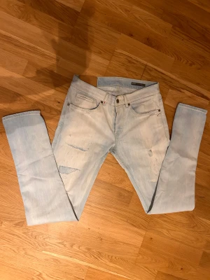 Ljusblå dondup jeans - Säljer ett par ljusblå  jeans från dondup med slitna detaljer Jeansen har en låg midja och smal passform, med snygga slitningar framtill och kontrastsömmar på bakfickorna. Perfekt för dig som gillar en avslappnad streetstil. W33 l32