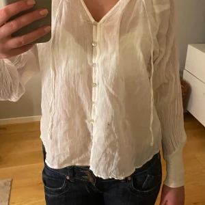 Vit blus - en vit, tunn blus med v-ringning och knappar