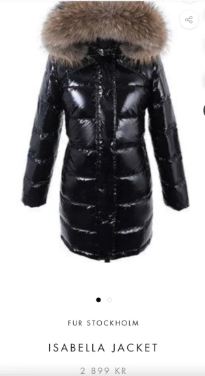 Svart Isabella pufferjacka med päls - Isabella Jacket från Fur Stockholm är en svart, glansig pufferjacka med lång passform och stor huva med fluffig päls. Jackan har quiltad design, dragkedja framtill och långa ärmar. Perfekt för kalla vinterdagar och ger en cool look. Använd 3ggr, som ny! 