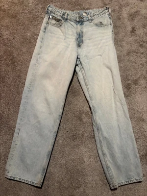 Ljusblå raka jeans - Säljer ett par ljusblå jeans med klassisk femficksdesign och raka ben. Jeansen har normal passform och är tillverkade i mjukt denimtyg. Perfekt för dig som gillar en enkel och clean look.
