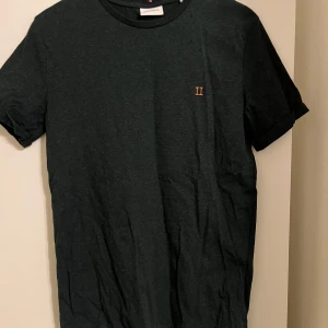 Svart t-shirt från Les Deux, M - Snygg svart t-shirt från Les Deux i storlek M. Klassisk rund hals och korta ärmar, med en liten broderad II-logga i orange på bröstet. Tillverkad i mjuk bomull som känns skön mot huden. Nästan aldrig använd 