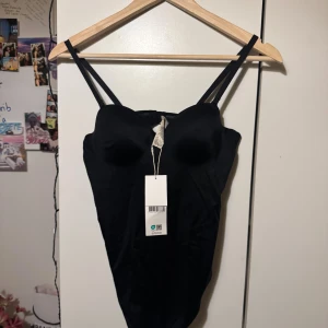 Svart body från Zalando med kupor - Snygg svart body  med vadderade kupor och smala axelband. Modellen har en stilren, tight passform och en liten öppning i ryggen för extra detalj. Helt ny oanvänd prislapp kvar